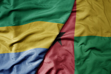 big waving national colorful flag of guinea bissau and national flag of gabon .