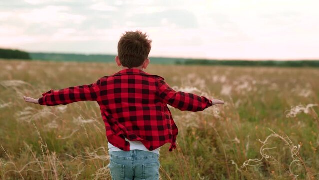 Cheerful boy runs along field with growing plants with incredible view of nature