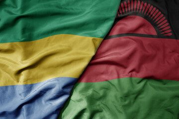 big waving national colorful flag of malawi and national flag of gabon .
