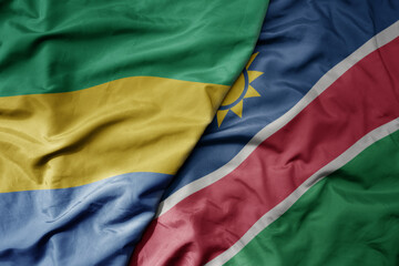 big waving national colorful flag of namibia and national flag of gabon .