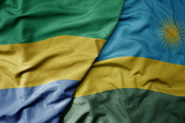big waving national colorful flag of rwanda and national flag of gabon .