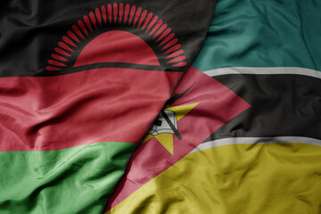 big waving national colorful flag of mozambique and national flag of malawi .