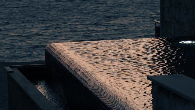 Beautiful seaside infinity pool reflects romantic sunset sky