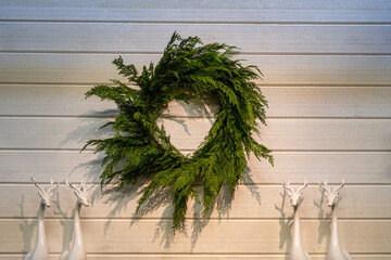 Rustic Christmas background, artificial cedar branch wreath on wall with reindeer
