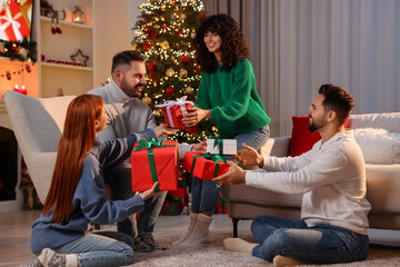 Christmas celebration. Happy friends exchanging gifts at home