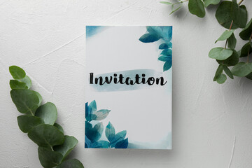 Beautiful card with word Invitation and eucalyptus leaves on white table, flat lay