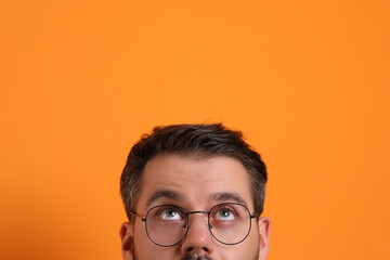 Man in stylish glasses on orange background, closeup
