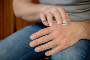 Hands of a man applying cream.