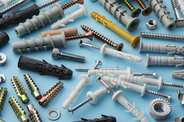 Many different fasteners and dowels on light blue background, above view - obrazy, fototapety, plakaty