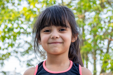 Close-up portrait of her. She is friendly, charming, sweet, curious and cheerful. Little girl outdoors in sports clothing.