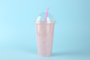 Plastic cup of tasty smoothie on light blue background