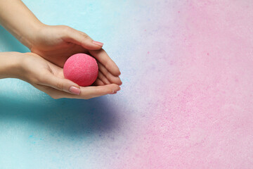 Woman holding bath bomb over water with foam, closeup. Space for text