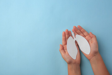 Child holding paper human lungs on light blue background, top view. Space for text