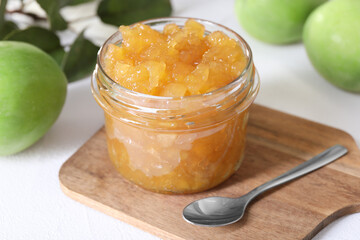 Glass jar of delicious apple jam and fresh fruits on white table