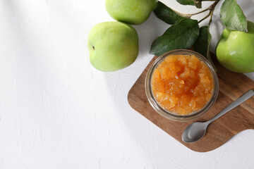 Glass jar of delicious apple jam and fresh fruits on white table, flat lay. Space for text