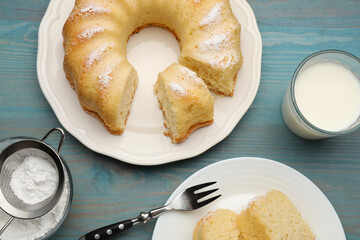 Delicious sponge cake served on light blue wooden table, flat lay