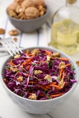 Tasty salad with red cabbage and walnuts at white table, closeup