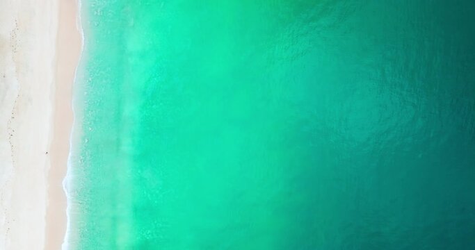 Aerial view of sea crashing waves White foaming waves on beach sand,Top view beach sea surface texture background,Amazing colorful beach sea wonderful sand background
