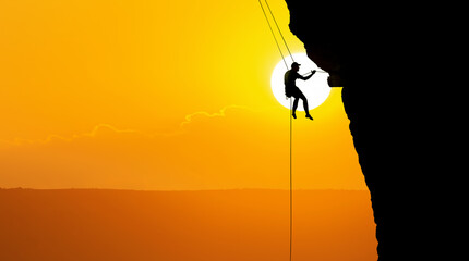 Silhouette of a rock climber against the backdrop of a warm, dusky sky - 679922757