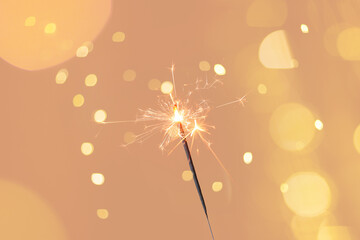 Beautiful Christmas sparkler on beige background with blurred lights