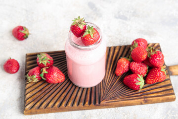 Mason jar of tasty strawberry smoothie on light background