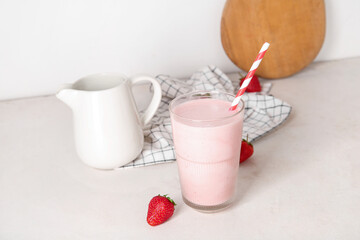 Glass of tasty strawberry smoothie on light background