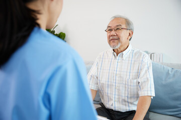 elderly man smiling and talking with caregiver on sofa