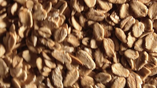 Oat Flakes Background Slowly Moving Upward - Top View, Low Key Light. Scattered Dry Oat Flakes. Healthy Breakfast and Diet Eating Ingredients