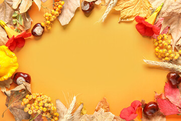 Frame made of autumn leaves with rowan, wheat ears and chestnuts on orange background