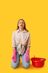 Beautiful young housewife with basin meditating on yellow background. Zen concept