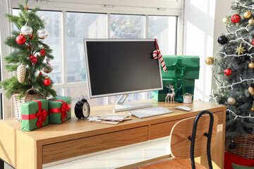 Workplace with computer monitor, presents and Christmas tree in office