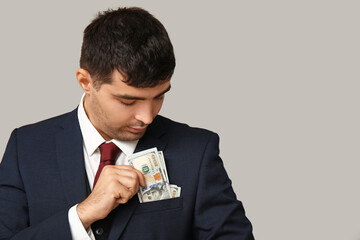 Young businessman with bribe in pocket on light background, closeup
