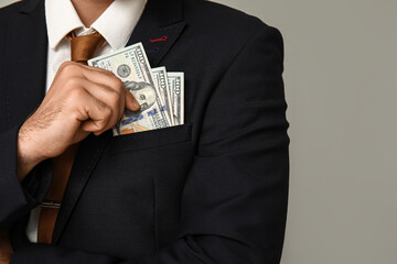 Young businessman with bribe in pocket on light background, closeup