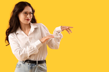 Young Asian gossip woman on yellow background