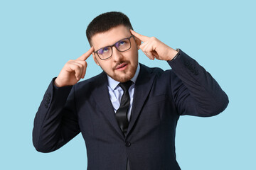Young thoughtful businessman on blue background. Business idea concept