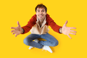 Young man opening arms for hug on yellow background