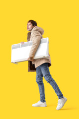 Young man with radiator on yellow background