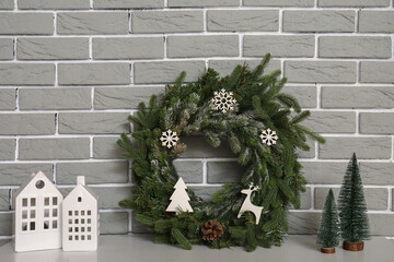 Christmas wreath with fir trees and candle holders on mantelpiece near grey brick wall