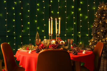 Festive dining table set for Christmas with burning candles and fir cones in room