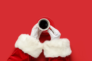 Santa Claus hands with cup of aromatic coffee on red background, closeup
