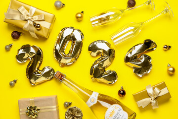 Composition with figure 2024 made of balloons, bottle of champagne and Christmas decorations on yellow background