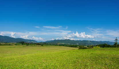 Green grass field and mountain view with blue sky. Nature background. Countryside landscape
