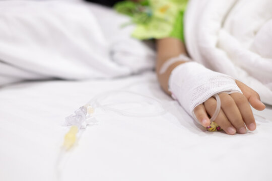 Child's hand fever patients have IV tube in hospital. Toddler girl wearing IV tube sleep in icu emergency bed room for leukemia coma from Cancer, Pediatric, Dengue fever. Sick children, infected.