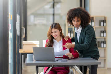 Two business woman using laptop talking and consulting working together in the office. Two business colleagues having a discussion during a meeting.