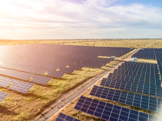 Aerial top view of a solar panels power plant. Photovoltaic solar panels at sunrise and sunset in countryside from above. Modern technology, climate care, earth saving, renewable energy concept.