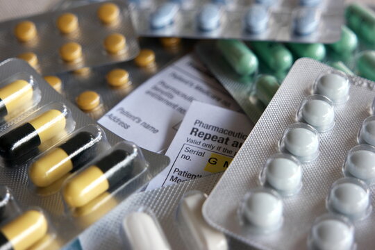 Medical Prescription covered with a bunch of different pills showing the state of healthcare of today.