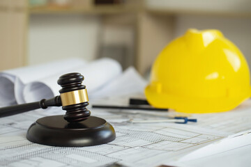 Labor and Construction law concept. judge gavel on building blueprint plans with a yellow safety...