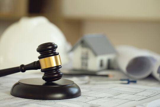 Labor and Construction law concept. judge gavel on building blueprint with safety helmet and house model in the background. law that deals with matters relating to building construction, engineering.