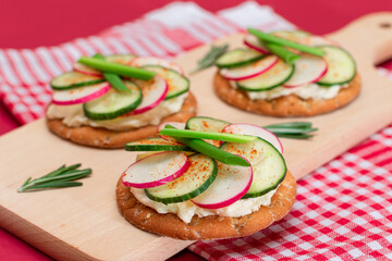 Light Breakfast or Diet Eating - Crispy Cracker Sandwich with Cream Cheese, Fresh Cucumber, Green Onions and Radish on Wooden Cooking Board on Magenta Background