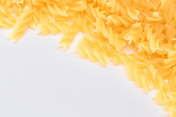 Fototapeta premium Uncooked Fusilli Pasta with Copy Space on White Background. Raw and Dry Macaroni. Fat and Unhealthy Food - Flat Lay